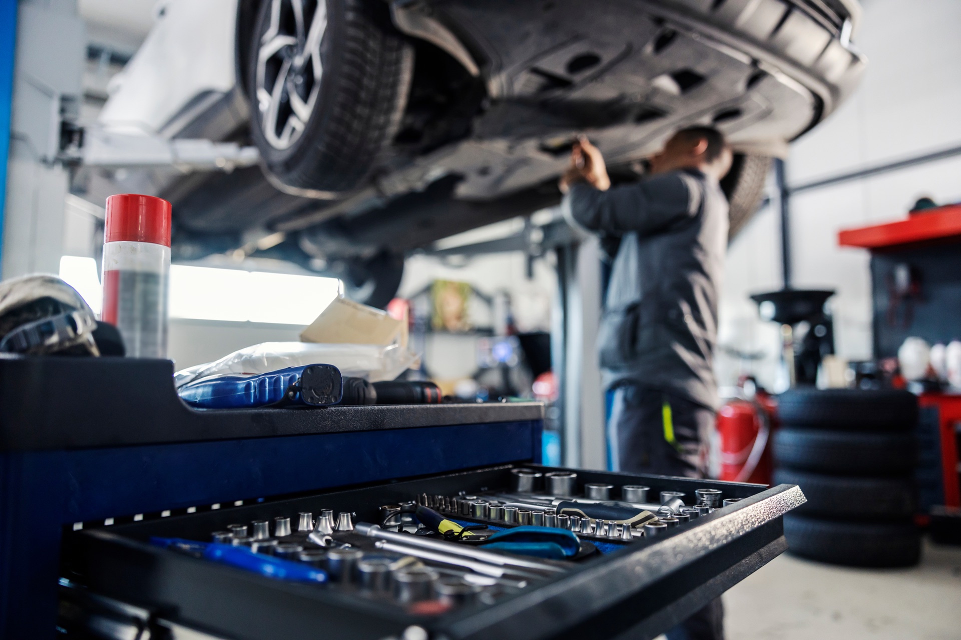 Mechanic servicing a vehicle above a professional tool cart
