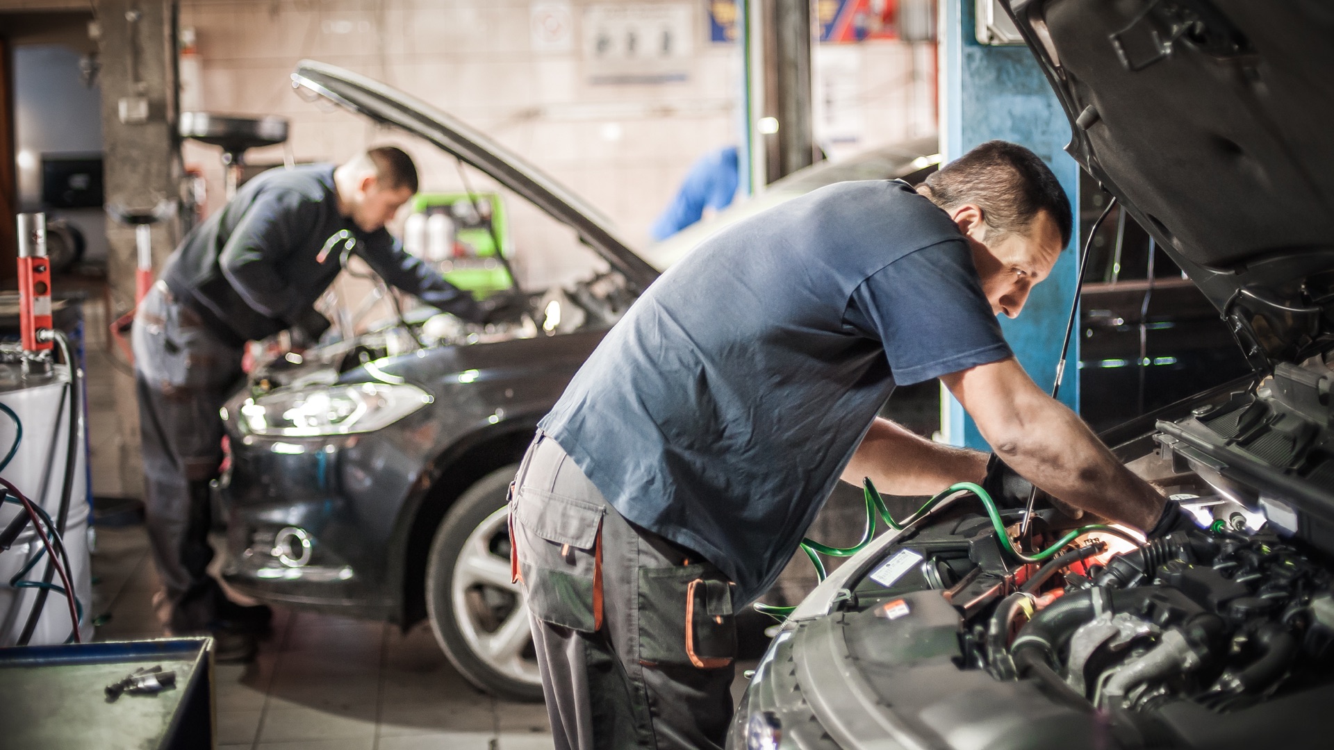 Auto technicians repairing vehicle engines in a busy workshop