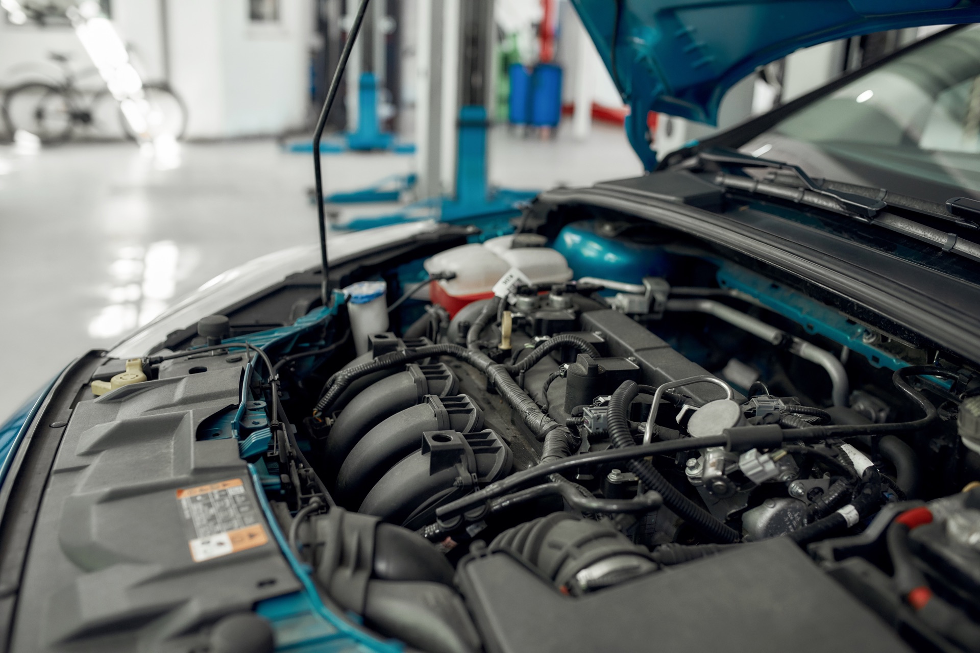 Open car hood and engine inside a professional auto repair shop